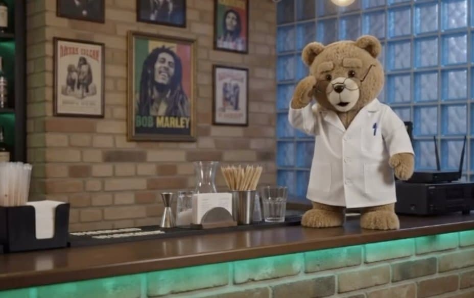 Ted the bear in a lab coat standing behind the club bar